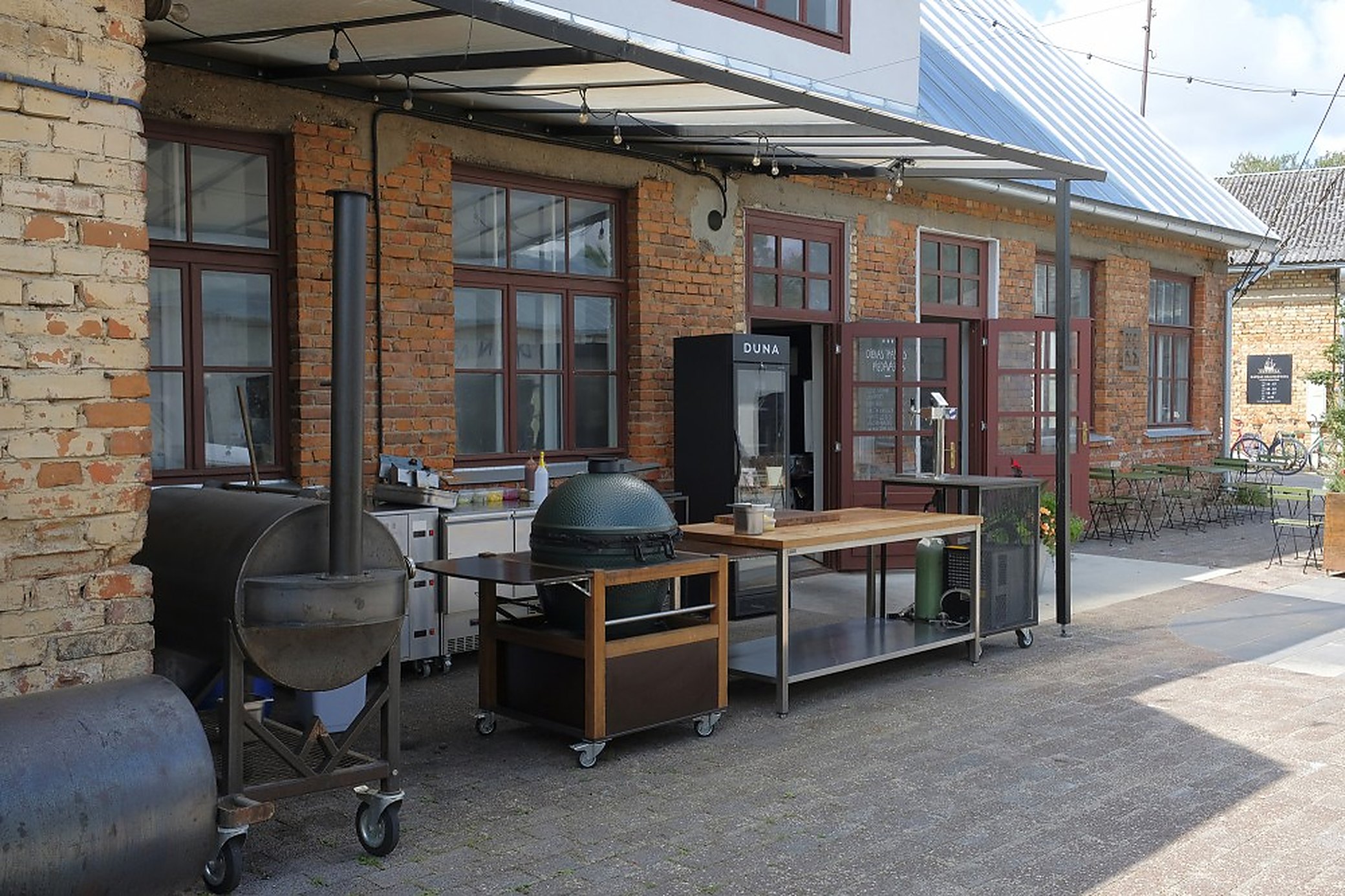 KOPA cooks outside through the summer. The smoker and the kamado live along the wall.