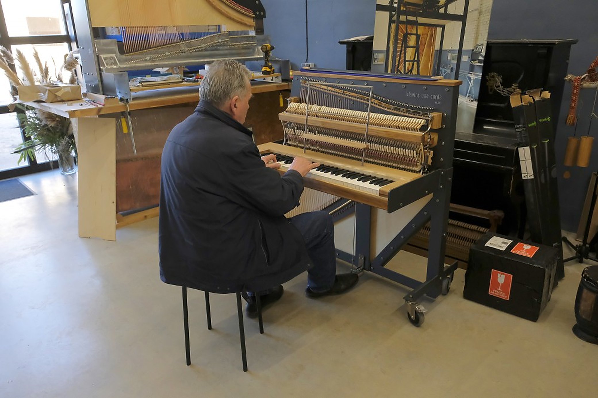 The workshop on Kaļķu iela 16, with an instrument up on the bench and someone at the keys.