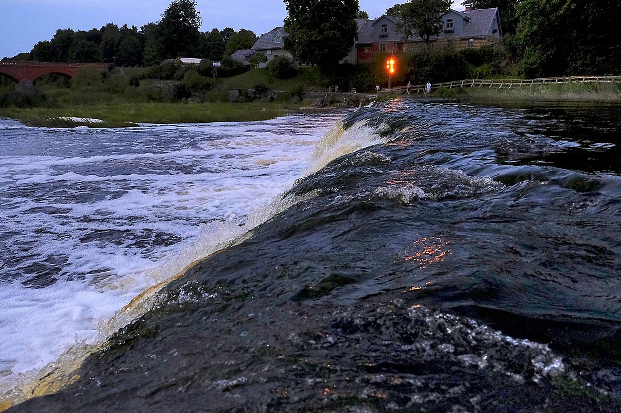 Late evening, the far bank lit. The noise carries into the old town well after dark.