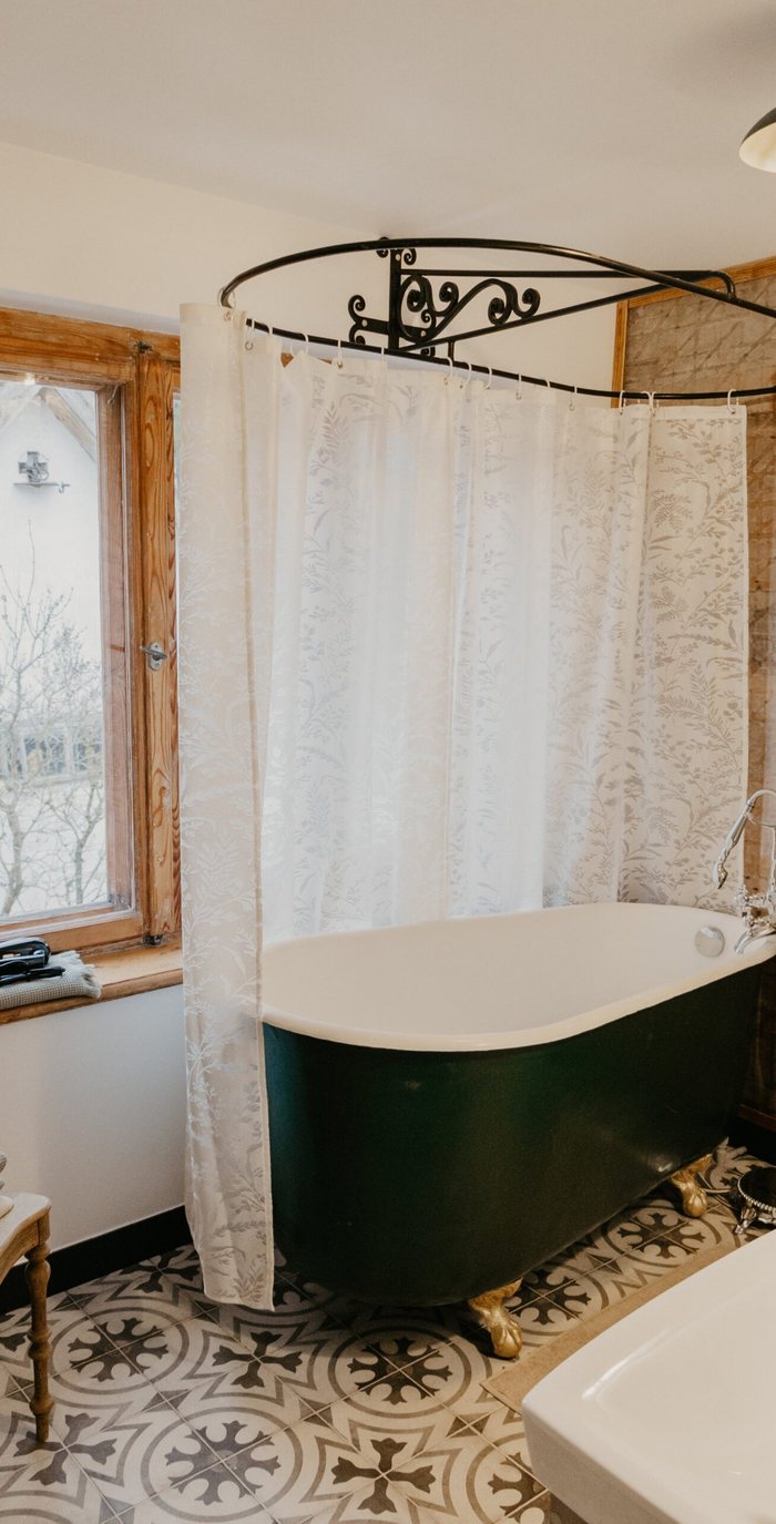 Freestanding green bathtub beneath a curtained window in the Straume apartment