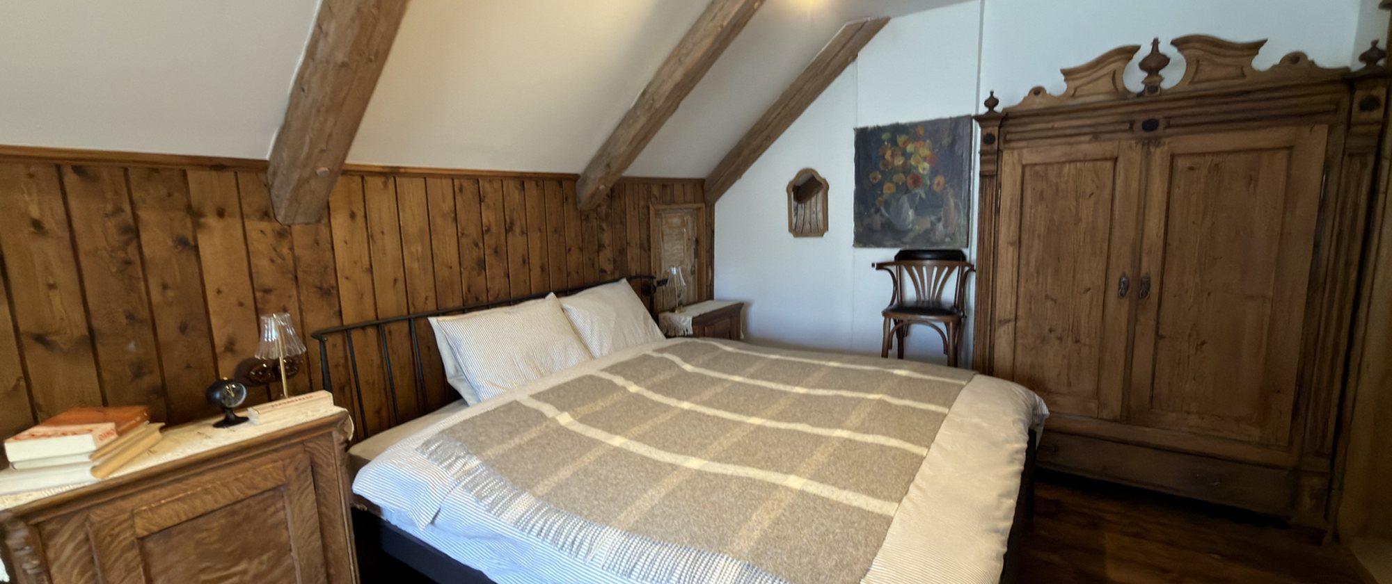 Bedroom under a sloped beamed roof in the Pils apartment